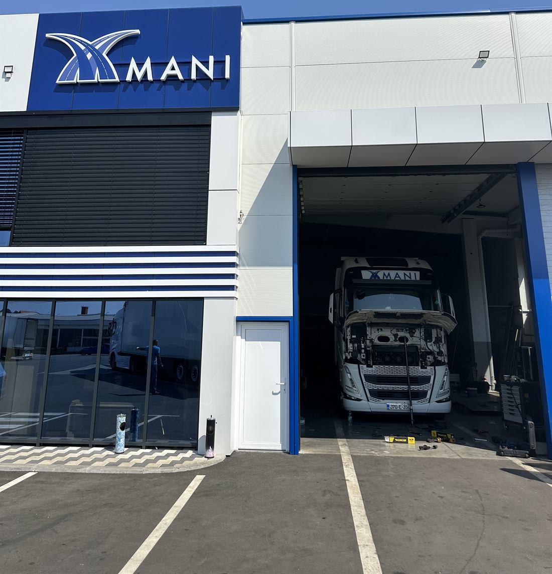 Sjedište MANI s logom na fasadi i Volvo kamionom u radionici
